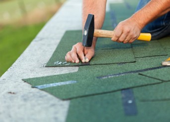 Worker hands installing bitumen roof shingles